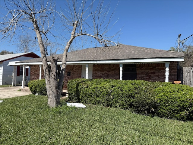 view of front of house with a front yard, brick siding, and roof with shingles