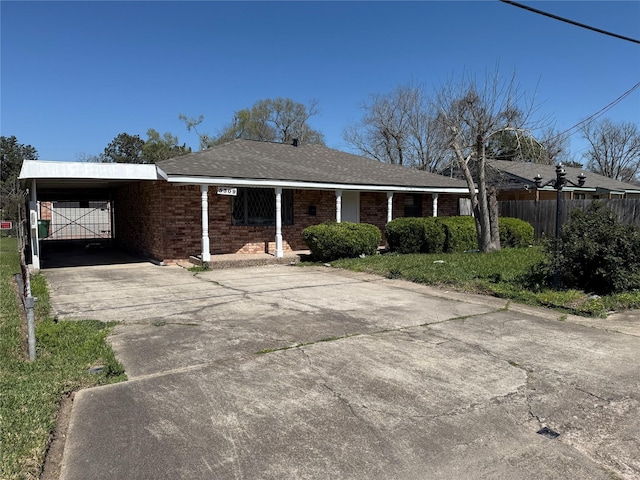 single story home featuring brick siding, an attached carport, driveway, and fence