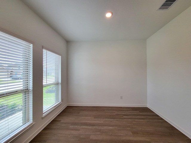 unfurnished room with visible vents, dark wood-type flooring, and baseboards