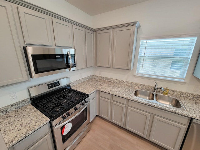 kitchen with a sink, gray cabinetry, and stainless steel appliances