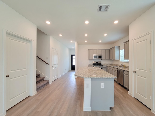 kitchen featuring visible vents, a sink, gray cabinetry, light wood-style floors, and appliances with stainless steel finishes