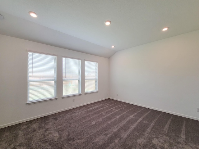 spare room with lofted ceiling, recessed lighting, baseboards, and dark colored carpet