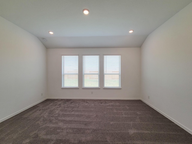 spare room with lofted ceiling, recessed lighting, baseboards, and dark carpet