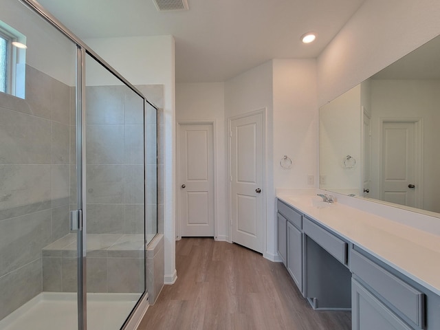 full bath featuring visible vents, wood finished floors, a stall shower, and vanity