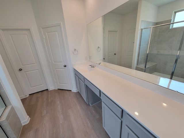 full bathroom featuring wood finished floors, vanity, and a tile shower