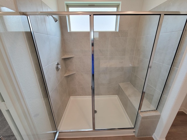 full bathroom featuring a stall shower and a textured wall