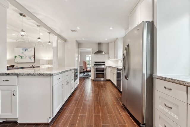 kitchen featuring visible vents, dark wood-style flooring, stainless steel appliances, decorative backsplash, and wall chimney exhaust hood