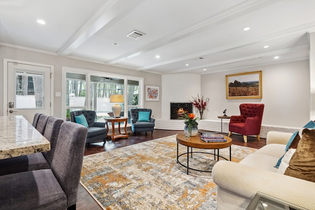 living area featuring visible vents, beamed ceiling, wood finished floors, a fireplace, and crown molding