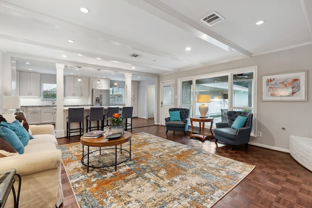 living room with visible vents, baseboards, beamed ceiling, and decorative columns