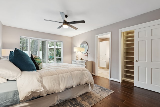 bedroom with a ceiling fan, baseboards, dark wood finished floors, a walk in closet, and connected bathroom