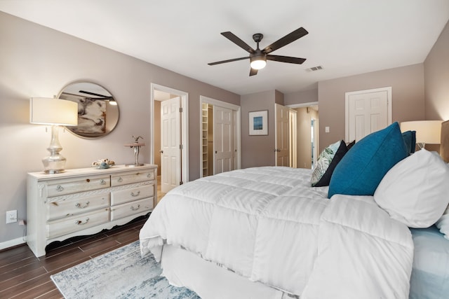 bedroom featuring visible vents, multiple closets, baseboards, wood tiled floor, and a ceiling fan