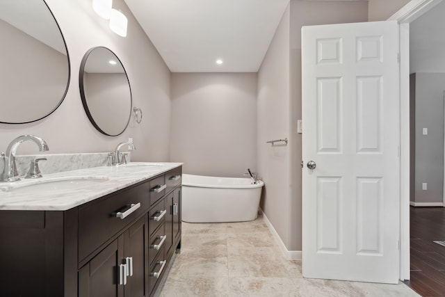 bathroom featuring double vanity, a freestanding bath, baseboards, and a sink