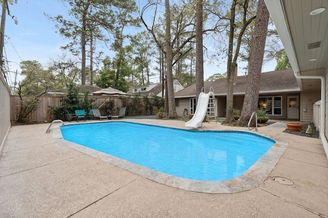 view of pool featuring a fenced backyard, a fenced in pool, a water slide, and a patio