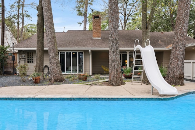 outdoor pool featuring a water slide, a patio, and fence