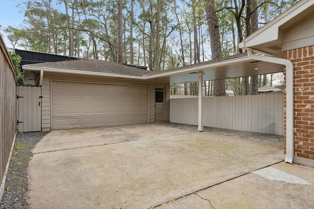 view of home's exterior featuring brick siding, driveway, an attached garage, and fence