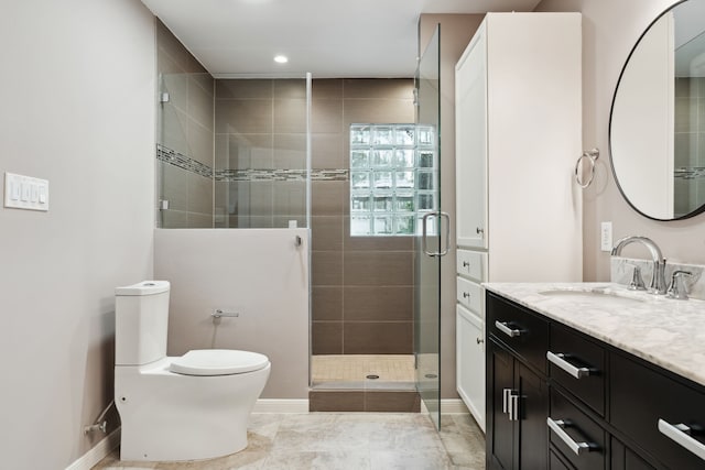 bathroom featuring a stall shower, toilet, vanity, and baseboards