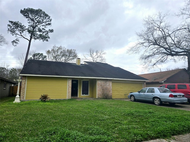 view of front facade featuring a garage, brick siding, a chimney, and a front yard