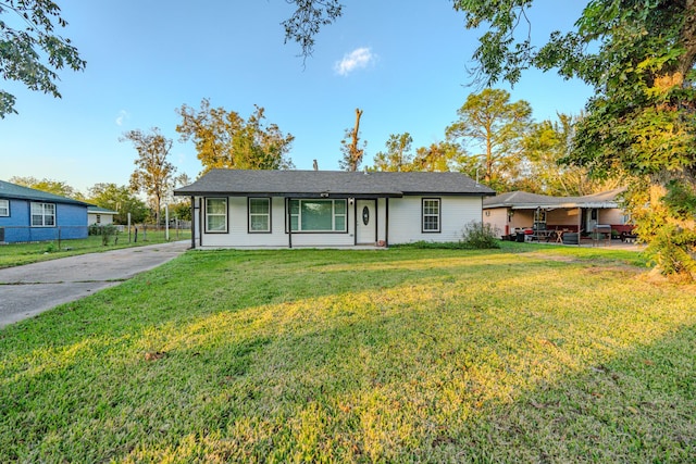 single story home with concrete driveway, a front lawn, and fence