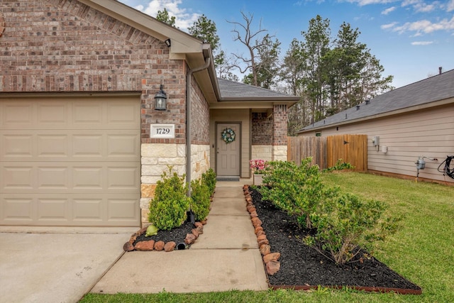 view of exterior entry featuring brick siding, fence, a yard, a garage, and stone siding