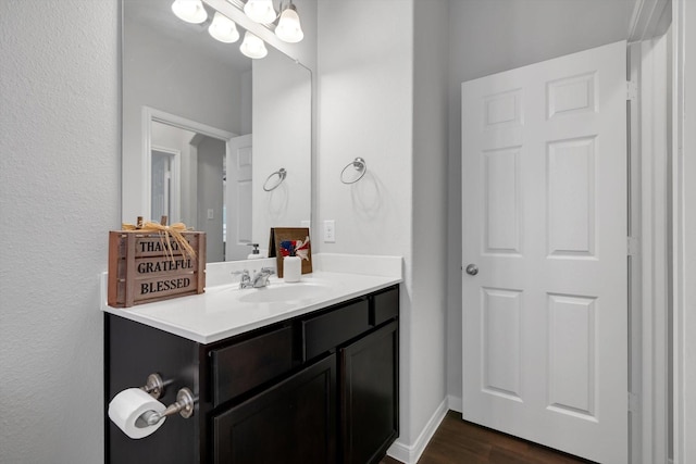 bathroom featuring vanity, wood finished floors, and baseboards