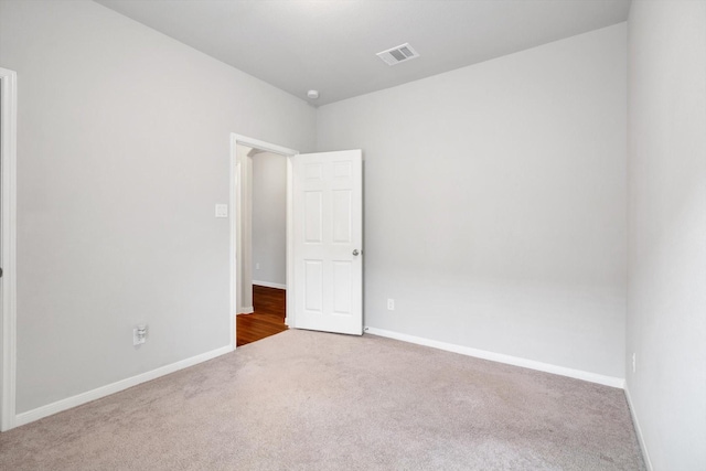 carpeted empty room featuring baseboards and visible vents