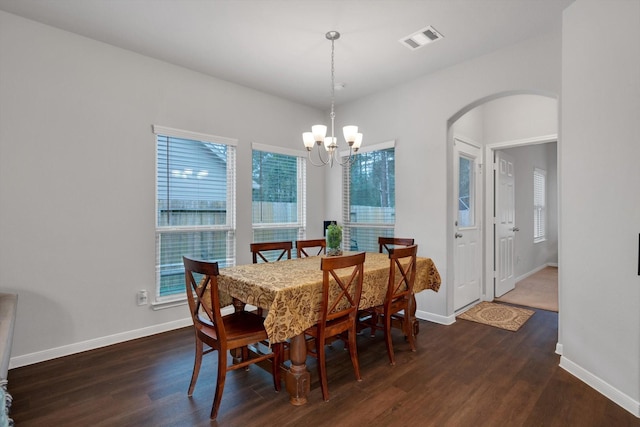 dining space featuring visible vents, wood finished floors, arched walkways, baseboards, and a chandelier