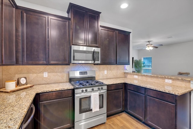 kitchen with backsplash, light wood-type flooring, light stone counters, a peninsula, and stainless steel appliances