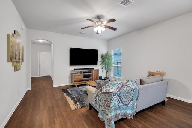 living room with a ceiling fan, visible vents, wood finished floors, baseboards, and arched walkways