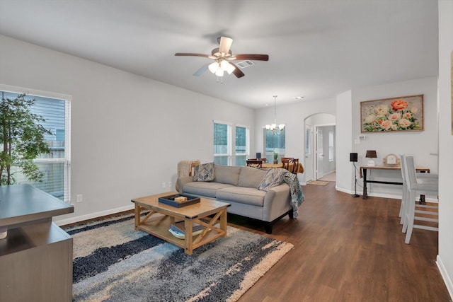 living room featuring baseboards, arched walkways, dark wood-style floors, and ceiling fan with notable chandelier