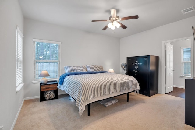 carpeted bedroom featuring visible vents, multiple windows, baseboards, and ceiling fan