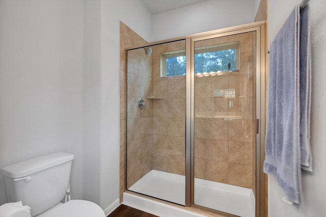 bathroom with toilet, baseboards, and a stall shower