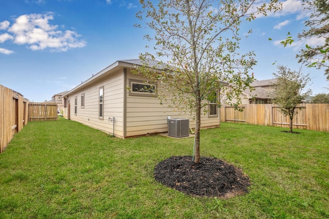 exterior space with a fenced backyard, a lawn, and central AC