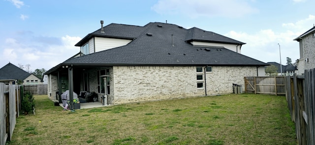 back of property with a yard, brick siding, a fenced backyard, and a patio area