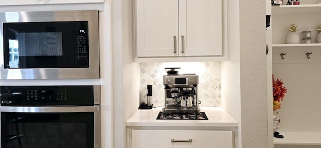 kitchen featuring stainless steel appliances, backsplash, light countertops, and white cabinetry