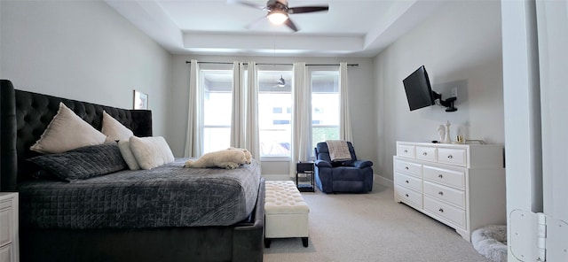 bedroom featuring a tray ceiling, a ceiling fan, baseboards, and light carpet