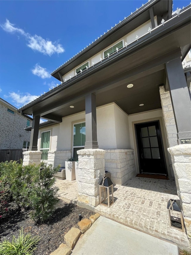 view of exterior entry with stucco siding and stone siding