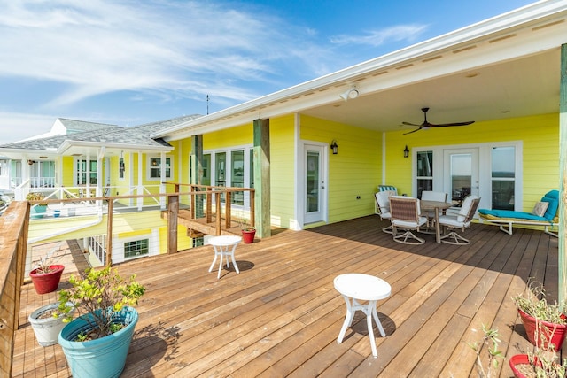 wooden terrace featuring french doors, outdoor dining area, and a ceiling fan