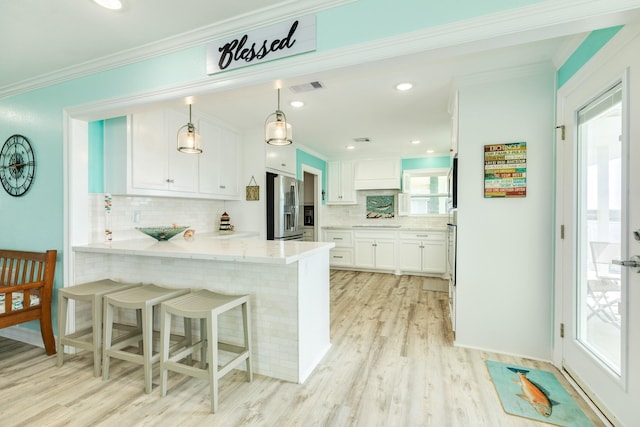 kitchen featuring visible vents, ornamental molding, white cabinetry, a peninsula, and stainless steel fridge with ice dispenser