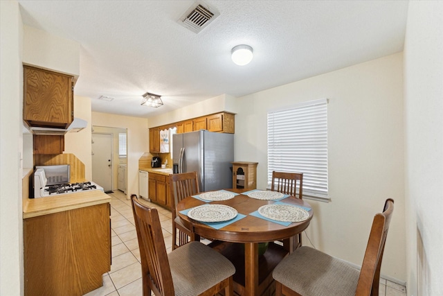 dining area with light tile patterned floors, washing machine and dryer, visible vents, and a textured ceiling