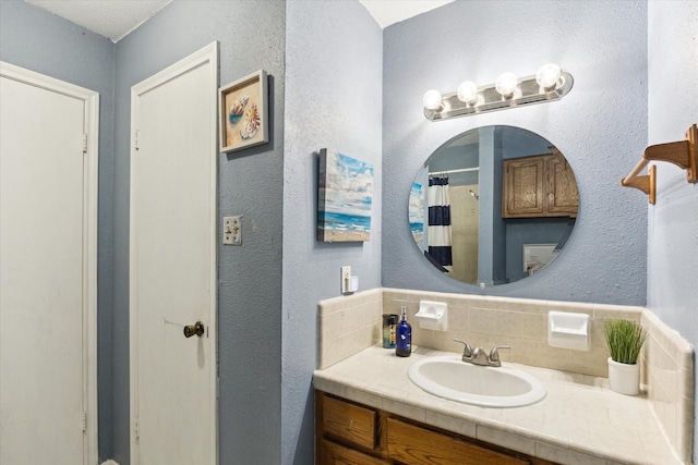 full bathroom with tasteful backsplash, vanity, a shower with curtain, and a textured wall