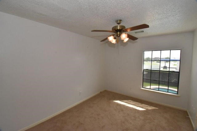 spare room featuring visible vents, baseboards, carpet flooring, a textured ceiling, and a ceiling fan