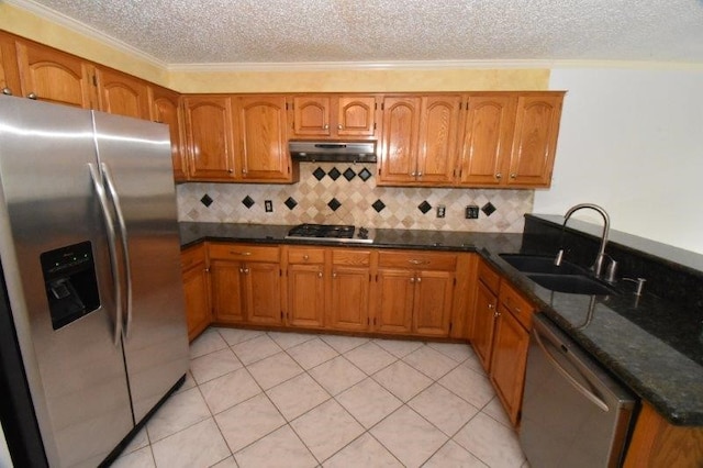 kitchen with under cabinet range hood, brown cabinets, appliances with stainless steel finishes, a peninsula, and a sink