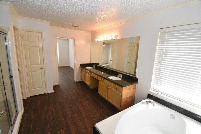 bathroom with a sink, a textured ceiling, wood finished floors, and a bath