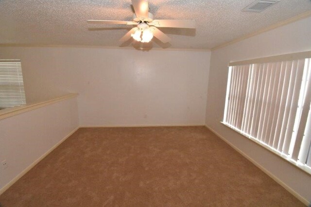 empty room featuring visible vents, carpet, ceiling fan, ornamental molding, and a textured ceiling