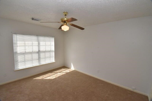 unfurnished room with visible vents, baseboards, a textured ceiling, and carpet flooring