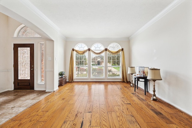 foyer featuring radiator, baseboards, light wood finished floors, and ornamental molding