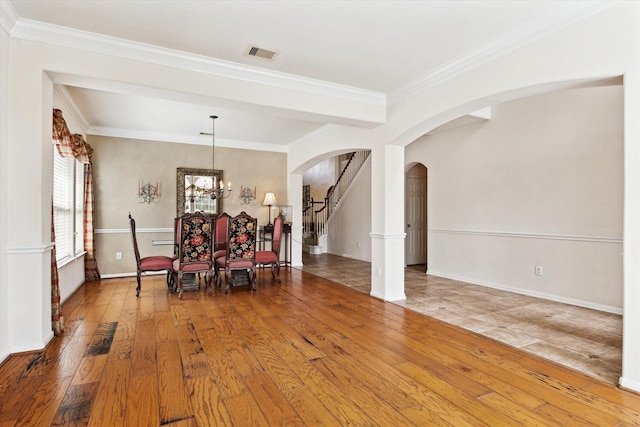 unfurnished dining area with visible vents, arched walkways, a notable chandelier, and hardwood / wood-style floors