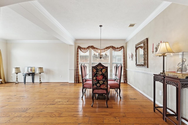 dining room with a chandelier, visible vents, ornamental molding, and hardwood / wood-style floors