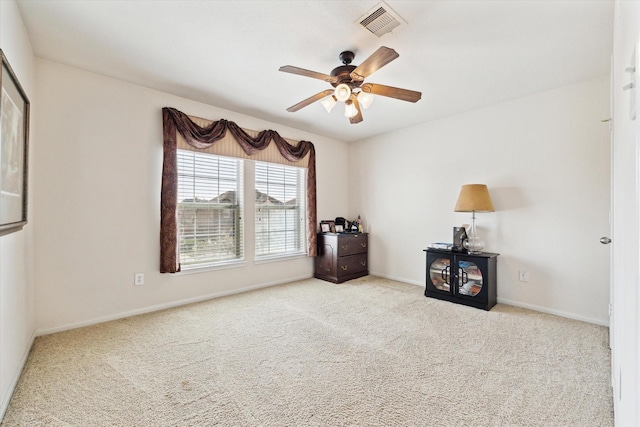 carpeted spare room featuring a ceiling fan, visible vents, and baseboards