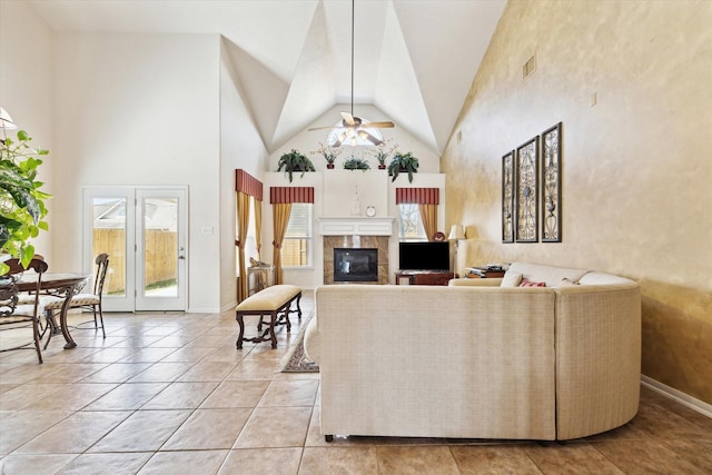 living area featuring visible vents, high vaulted ceiling, a ceiling fan, a tiled fireplace, and light tile patterned flooring